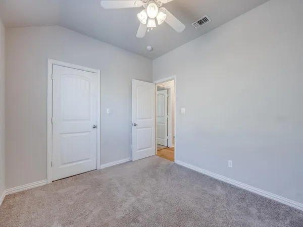 a view of an empty room and chandelier fan