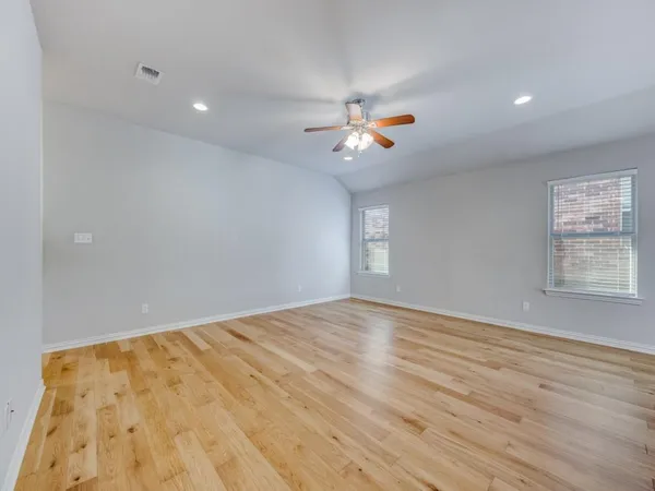 a view of empty room with wooden floor and fan