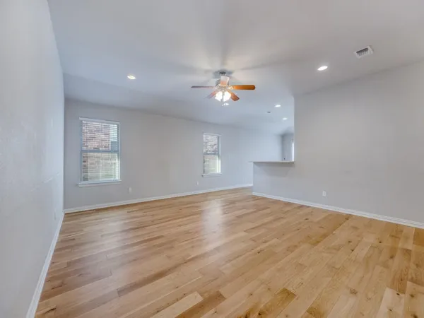 a view of an empty room with a window and wooden floor