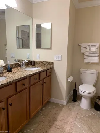 a bathroom with a granite countertop toilet sink and mirror