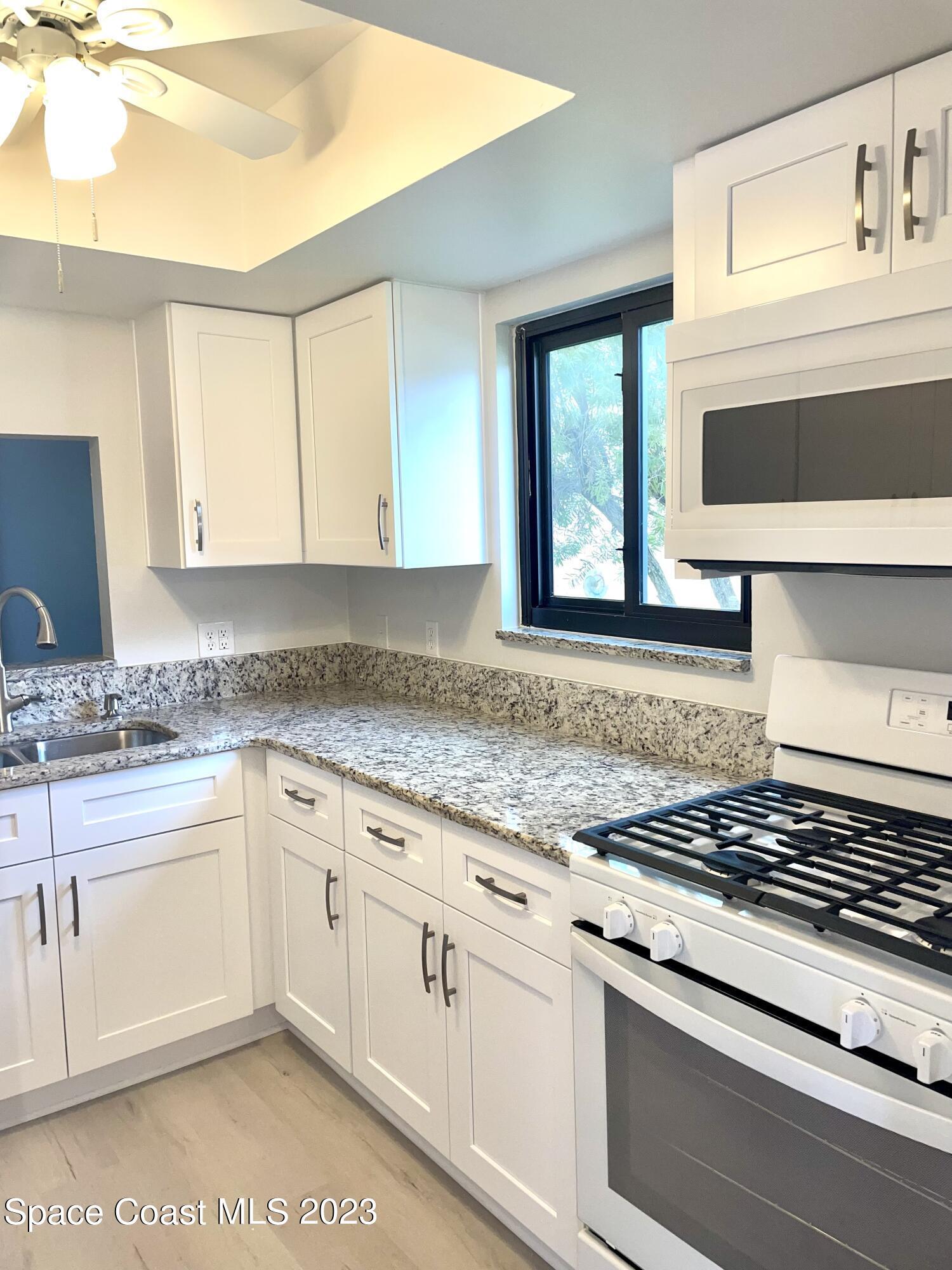 a kitchen with granite countertop white cabinets and white appliances