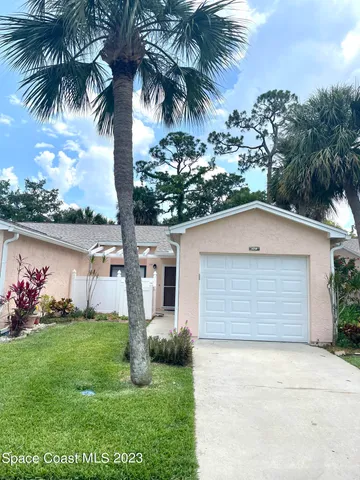 front view of house with a yard and palm trees