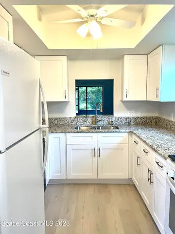 a white kitchen with granite countertop cabinets and a sink