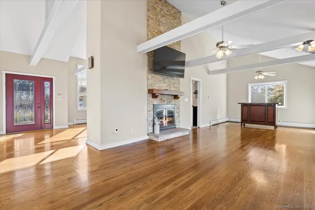 a view of an empty room with wooden floor and a kitchen