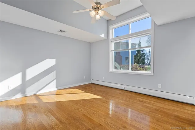 a view of an empty room with window and chandelier fan