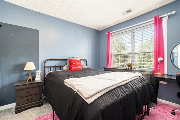 a bedroom with a bed and a dresser next to a window