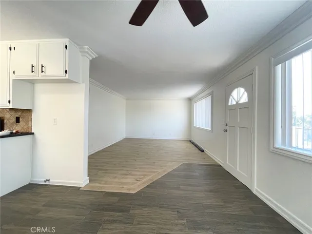 an empty room with windows and chandelier fan