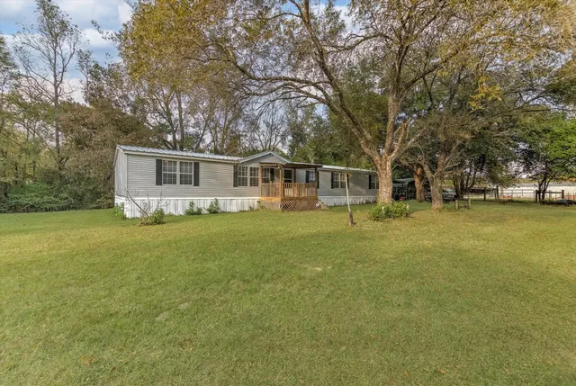 a front view of a house with a garden and trees