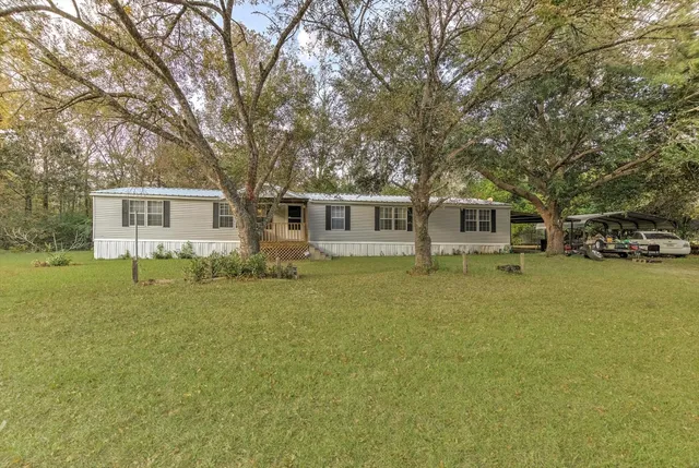 a front view of a house with a garden and tree