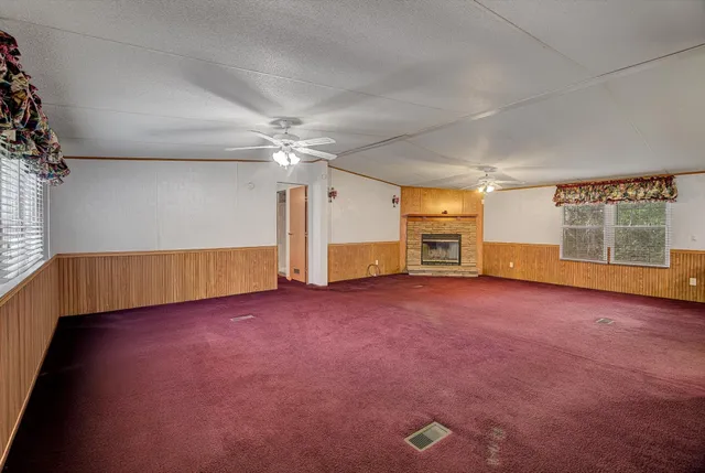 an empty room with windows and chandelier fan