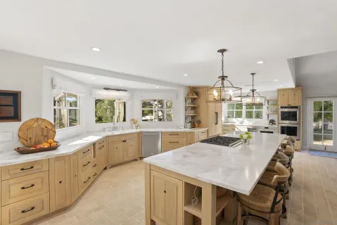 a large kitchen with granite countertop a stove a sink a dining table and chairs