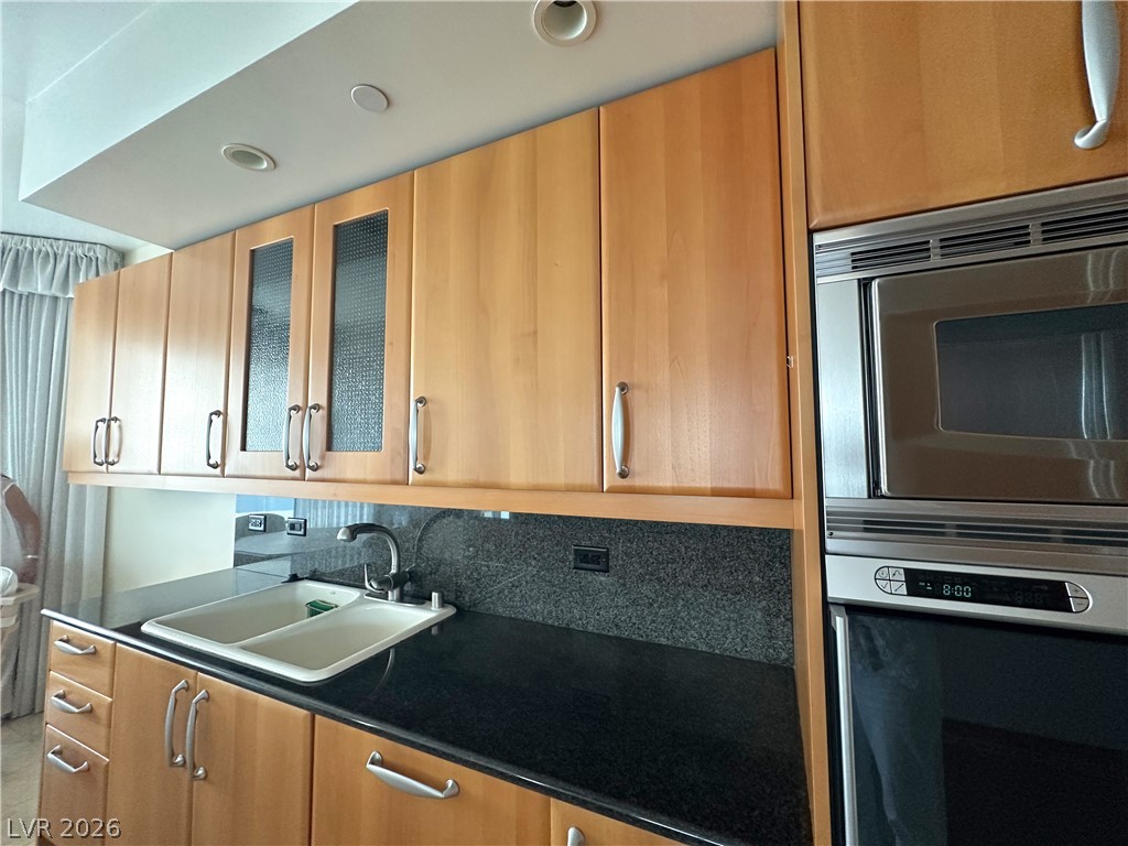 2747 Paradise Road, Unit 1706 Las Vegas, NV 89109 - Photo 14 of 35 A well-appointed kitchen features ample light wood cabinetry, sleek dark countertops, and integrated stainless steel appliances.