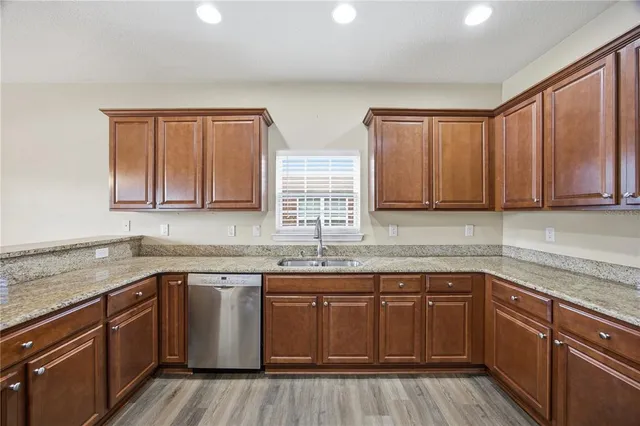 a kitchen with stainless steel appliances granite countertop wooden cabinets a sink and dishwasher with wooden floor