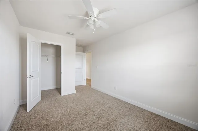an empty room with a ceiling fan and window