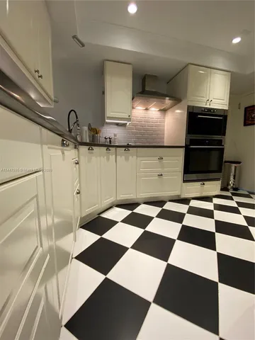 a kitchen with a checkered floor and white cabinets