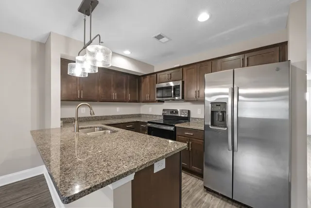 a kitchen with granite countertop a sink a counter space and cabinets
