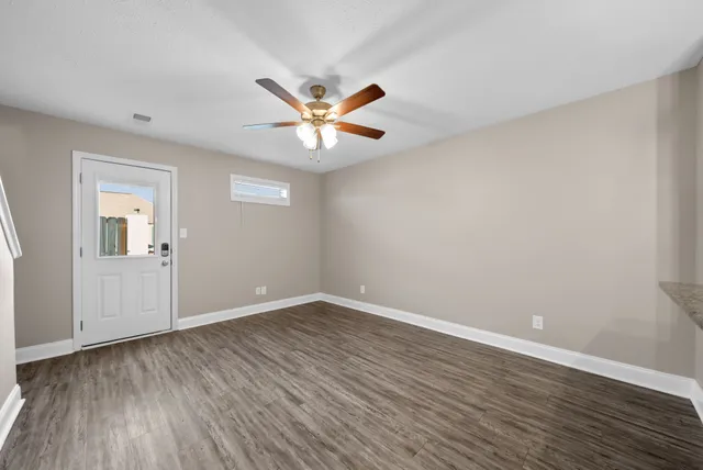 a view of an empty room with wooden floor and a ceiling fan