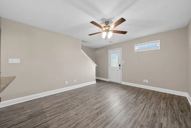 a view of a hallway with wooden floor and a bathroom