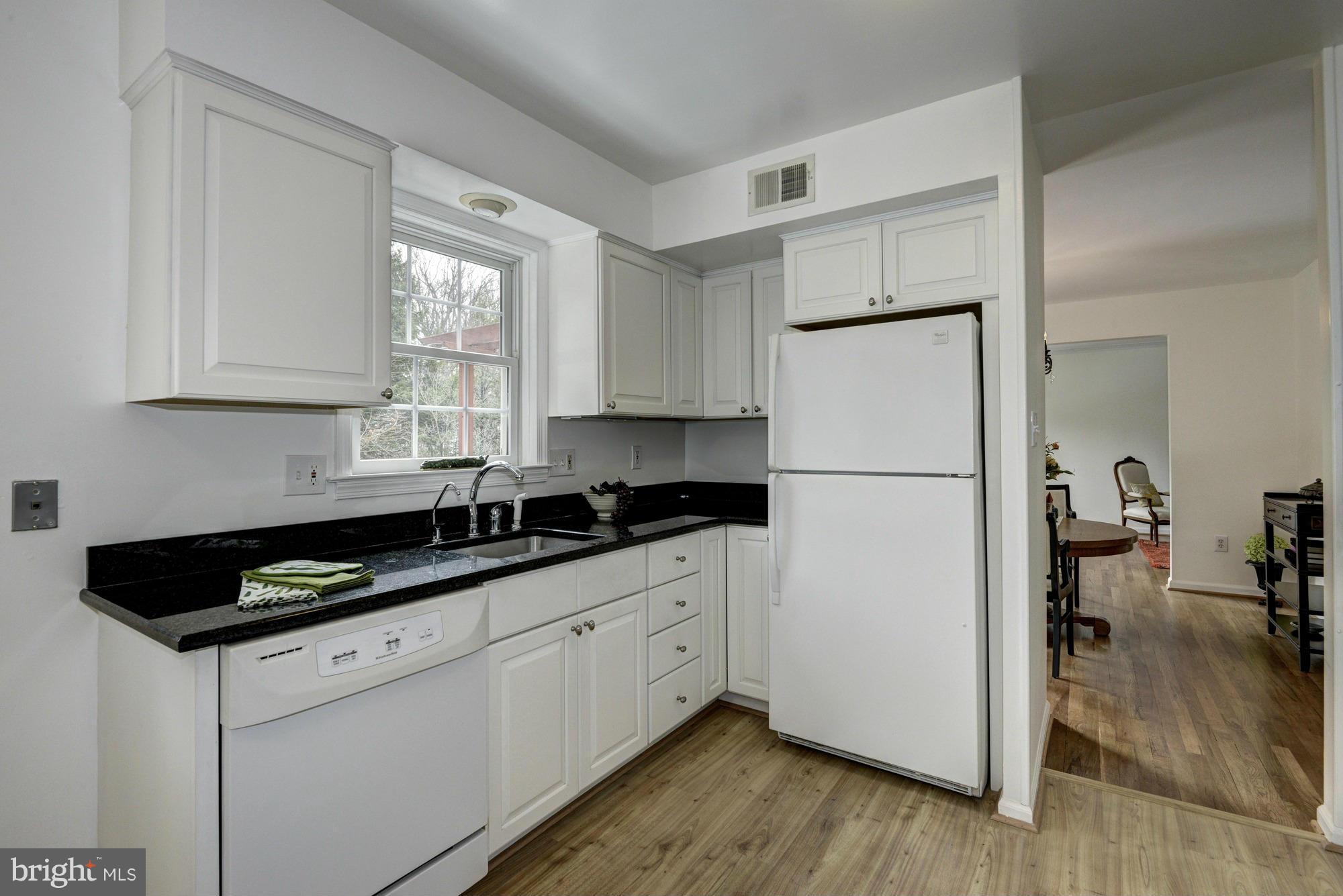 14117 Sturtevant Road Silver Spring, MD 20905 - Photo 6 of 30 a kitchen with granite countertop a refrigerator a sink and white cabinets