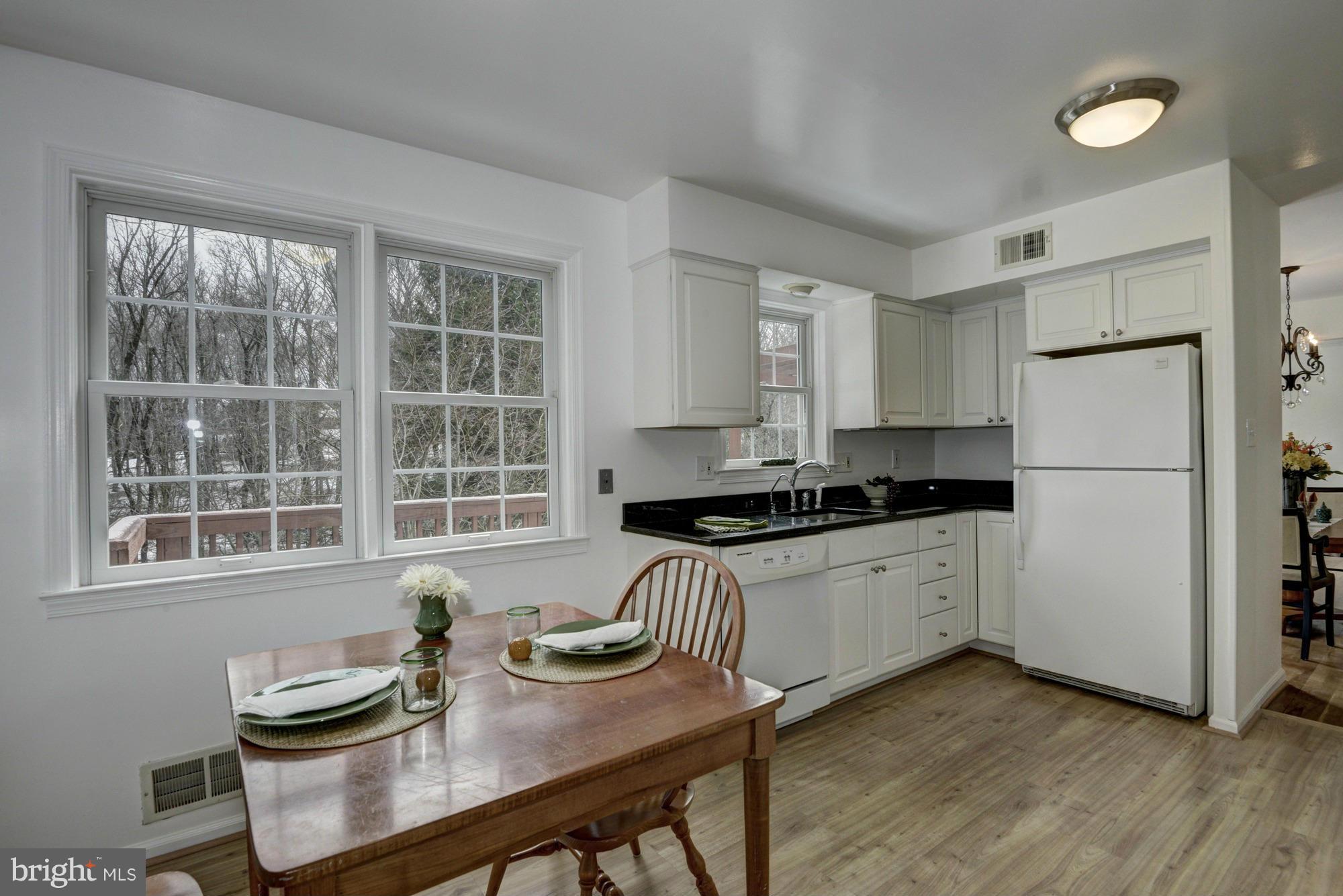 14117 Sturtevant Road Silver Spring, MD 20905 - Photo 7 of 30 a kitchen with stainless steel appliances granite countertop a stove a refrigerator a white table and chairs
