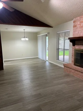 an empty room with wooden floor fireplace and windows