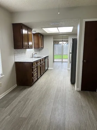 a kitchen with stainless steel appliances granite countertop a refrigerator a sink dishwasher a stove and a wooden floor