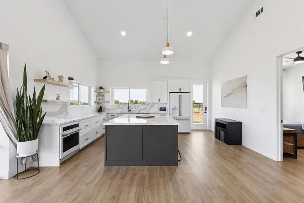 a large kitchen with cabinets wooden floor and stainless steel appliances