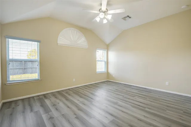 a view of an empty room with a window and wooden floor
