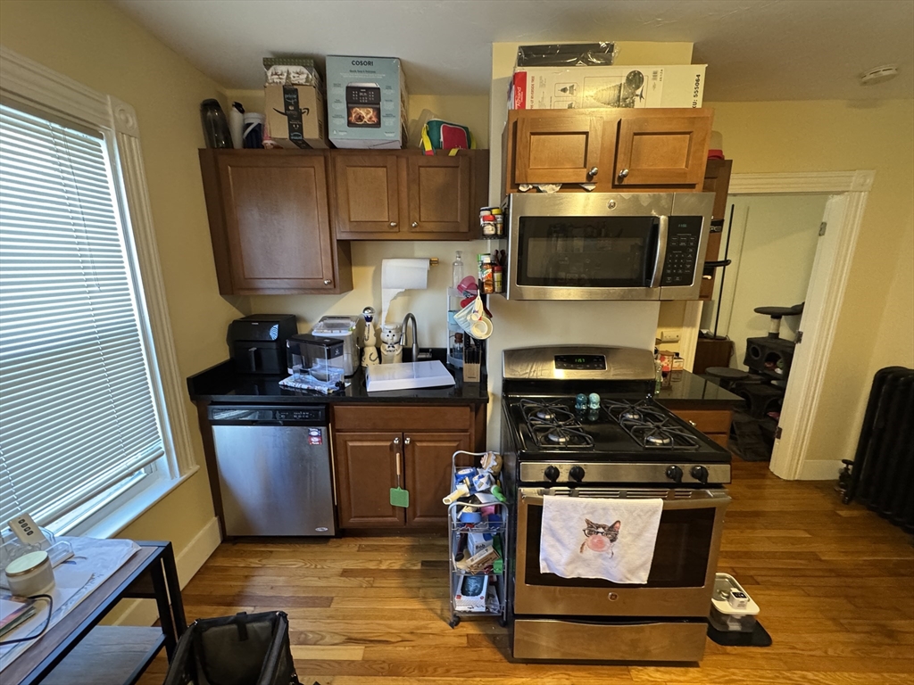 5 Blake Street, Unit 1 Cambridge, MA 02140 - Photo 36 of 41 a kitchen with stainless steel appliances a stove a microwave and a refrigerator