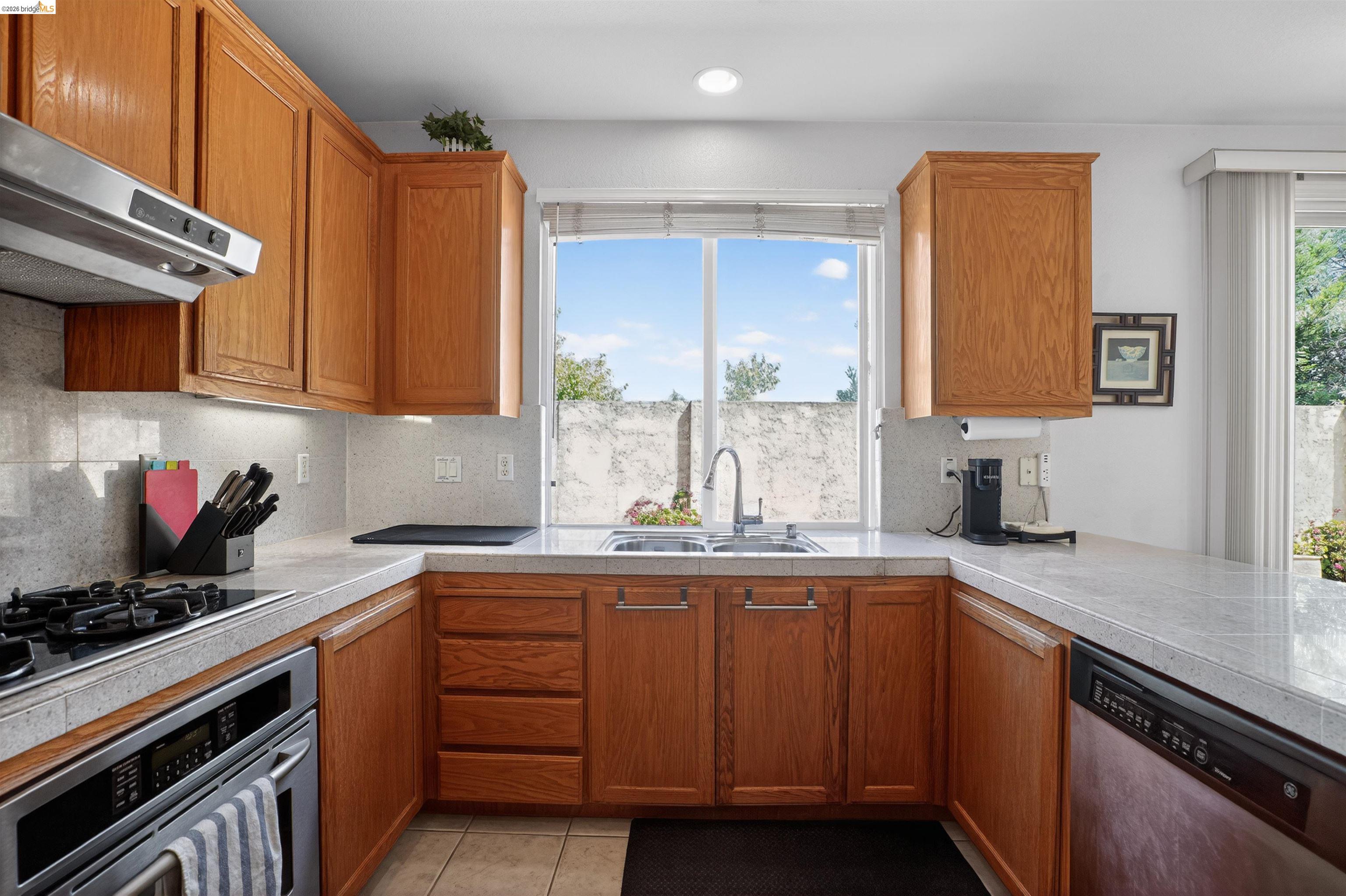 1221 Andrea Way Vallejo, CA 94591 - Photo 8 of 29 U-shaped kitchen featuring wood cabinetry, stone-finish countertops, and a tile backsplash