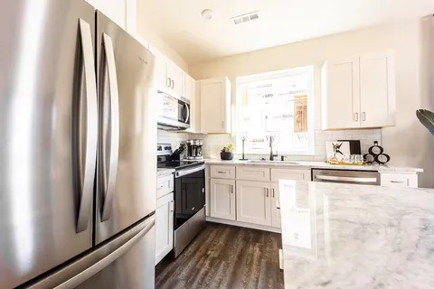 a kitchen with stainless steel appliances granite countertop a stove a sink and a refrigerator