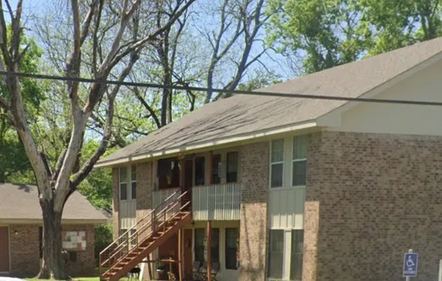 a side view of a house with a tree