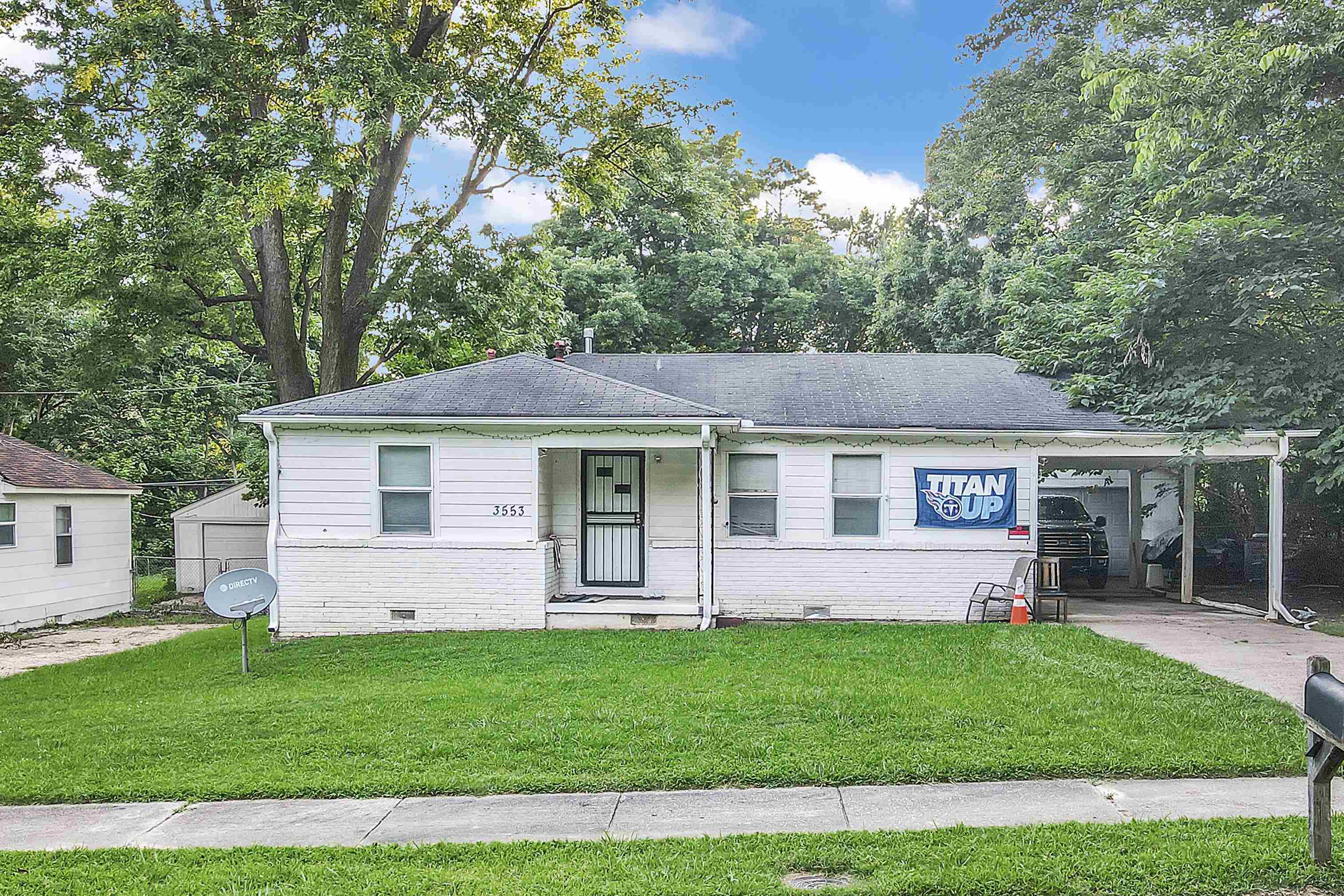 View of front of property with crawl space, a front lawn, a carport, and brick siding