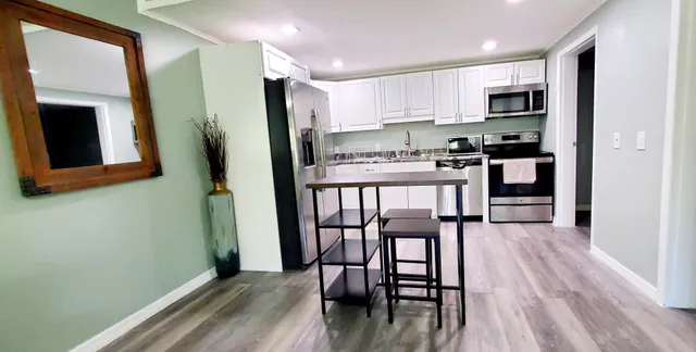 a kitchen with stainless steel appliances a microwave a stove a refrigerator and a dining table