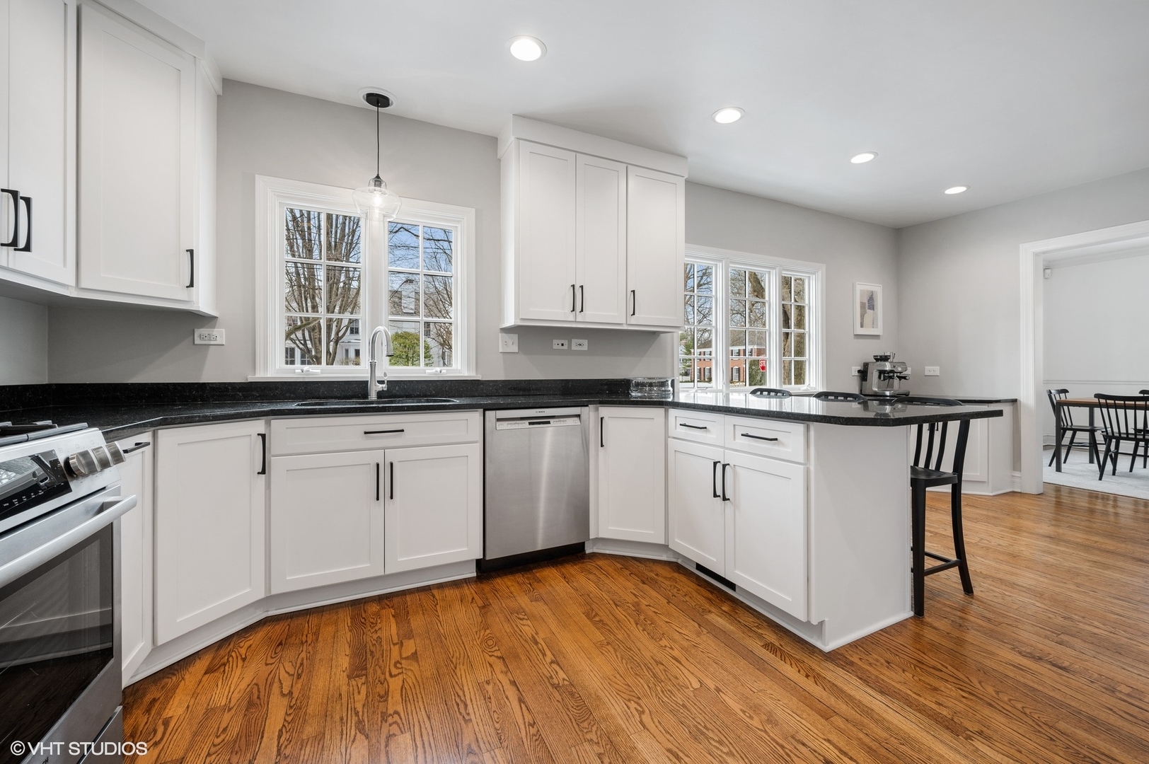402 Willow Road Winnetka, IL 60093 - Photo 7 of 31 a kitchen with granite countertop a stove a sink and white cabinets with wooden floor