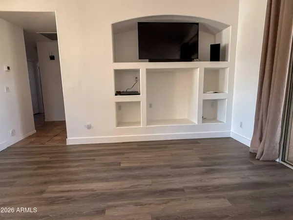 a view of an empty room with wooden floor and closet