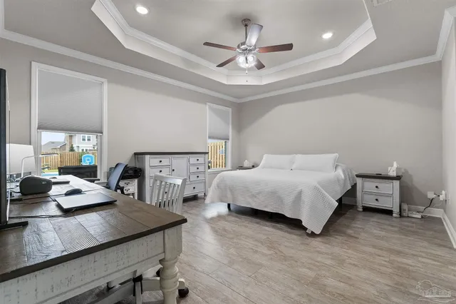 a bedroom with a bed a desk and chair with wooden floor