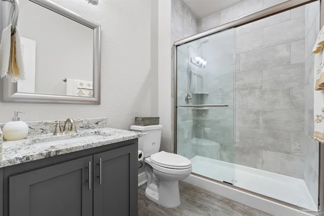 a bathroom with a granite countertop sink toilet and shower