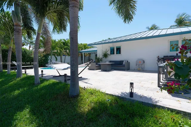 a view of a white house with a yard and palm trees