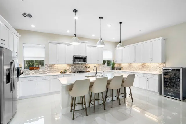 a room with stainless steel appliances kitchen island a table chairs sink and cabinets