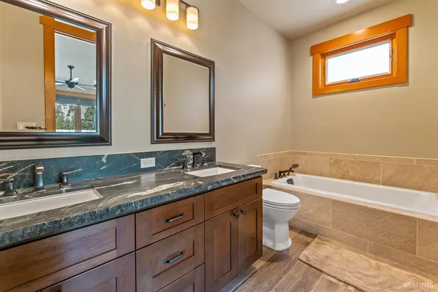a bathroom with a granite countertop toilet a sink and mirror