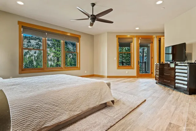 a spacious bedroom with a large bed a flat tv screen and large window