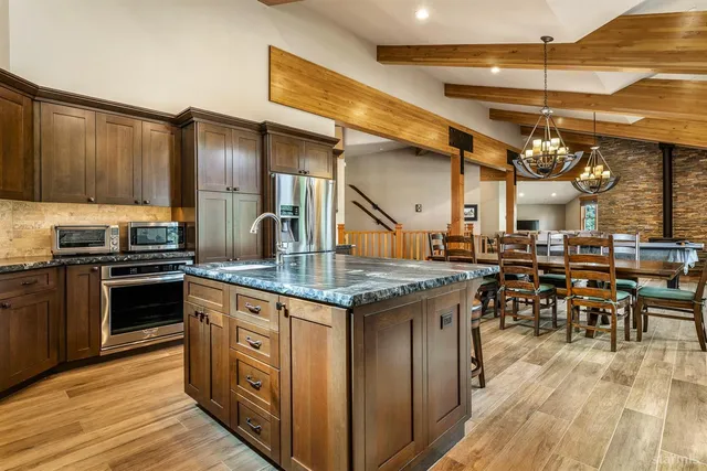 a dining room with wooden floor a chandelier a wooden table and chairs