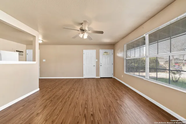 a view of empty room with wooden floor and fan