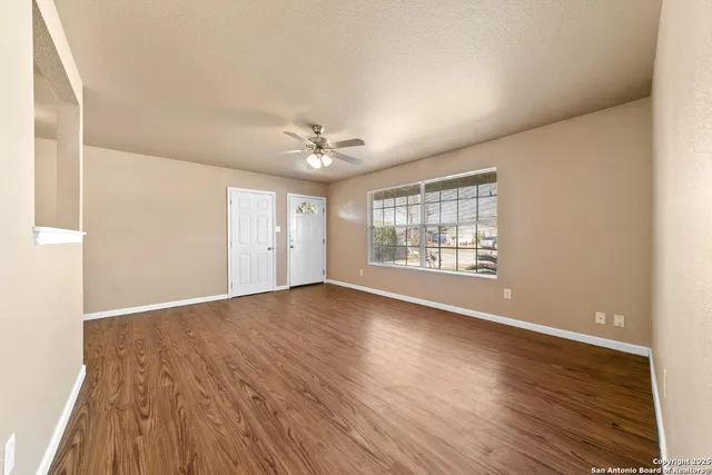 a view of an empty room with wooden floor and a window