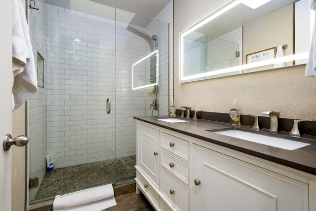 a bathroom with a granite countertop sink a mirror and shower