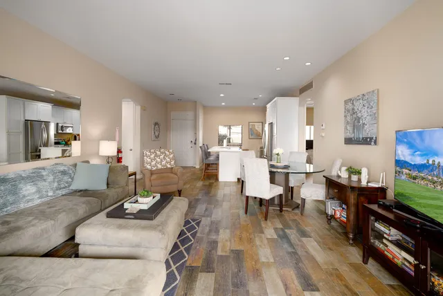 a living room with furniture and a dining table with wooden floor