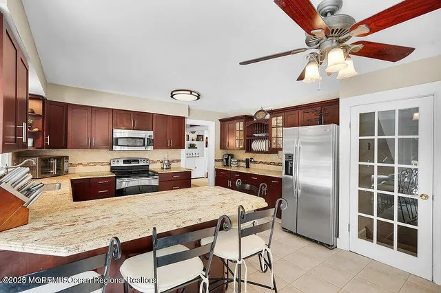 a kitchen with stainless steel appliances granite countertop a refrigerator a stove a sink dishwasher a dining table and chairs with wooden floor