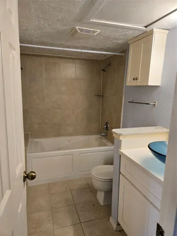 a bathroom with a granite countertop bathtub shower sink vanity and toilet