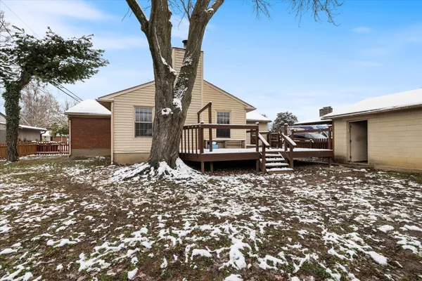 a backyard of a house with wooden fence and a large tree